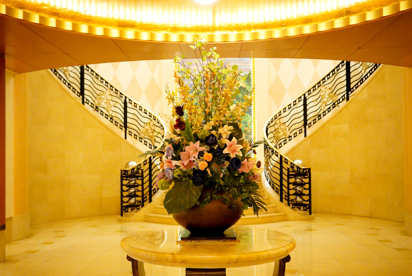 ホテルの一室に向かう階段が二手に分かれており、中央には様々な花が添えられた大きな花瓶が置かれています